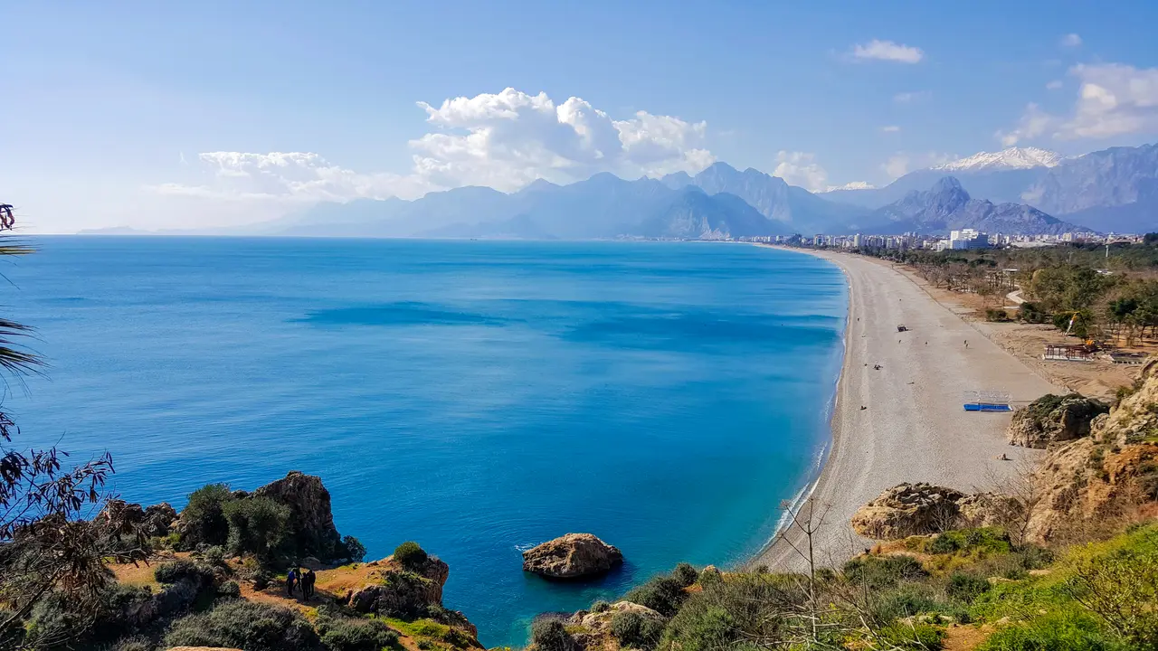 Konyaaltı Beach curving below the cliffs with the Taurus mountains behind